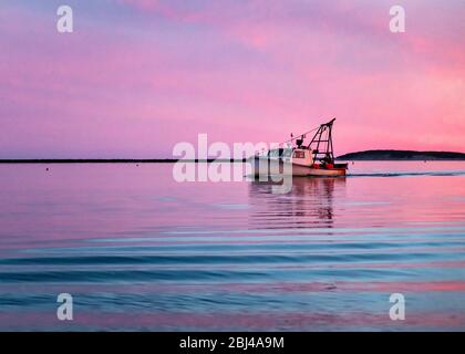 Commercial fishing boat returns to harbor at sunset at Wellfleet in Cape Cod. Stock Photo