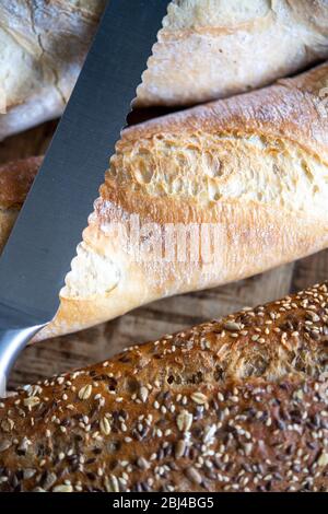Selection of freshly baked baguettes with bread knife Stock Photo