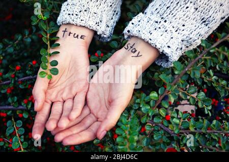 Female hands with written words on them against green plant background Stock Photo