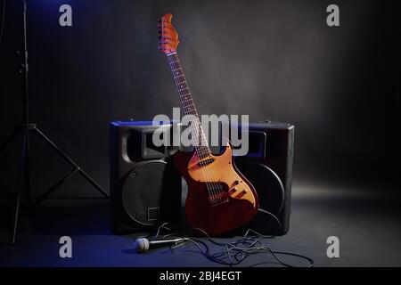 Big loudspeakers with electric guitar and microphone in dense smoke on black background Stock Photo