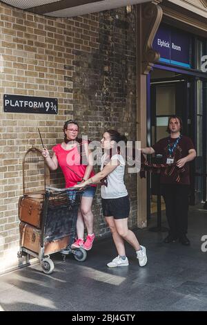 London/UK-26/07/18: tourists photographing near the imitated entrance to Platform 9 3/4. King's Cross railway station platform 9 3⁄4 is hidden from v Stock Photo