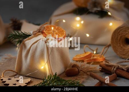 Zero waste christmas concept. Packed in natural fabric gifts and decorations from natural materials with christmas lights. Stock Photo