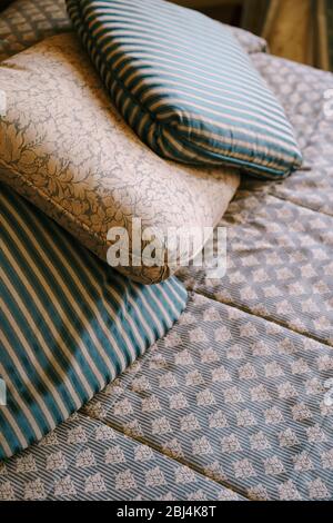 Pillows on the bed. A pillow with a pattern and two pillows with stripes lie on an old wooden bed Stock Photo