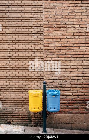 Two garbage cans - yellow and blue, against the background of a brick wall. Association with the flag of Ukraine, like the Ukrainian flag. Stock Photo