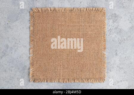 Piece of burlap on a gray concrete table. Template for design in eco style. Place for text, copy space. Stock Photo