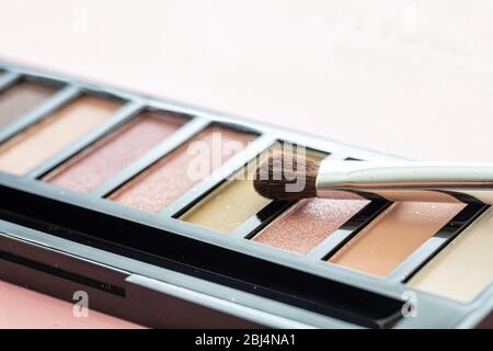 Eyeshadows pallete set pastel brown colors and brush against pink background, closeup view. Professional tools for make up, beauty salon, cosmetics co Stock Photo