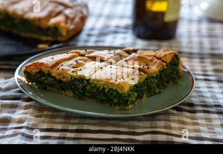 Healthy food concept. Spinach pie or greek spanakopita serving on kitchen table background, closeup view. Stock Photo