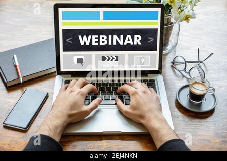 Webinar, online training and education, distance learning concept. Back view of a man working with a computer laptop, webinar text on the screen Stock Photo