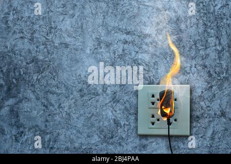 On fire charger adapter on the concrete wall exposed concrete background with space Stock Photo