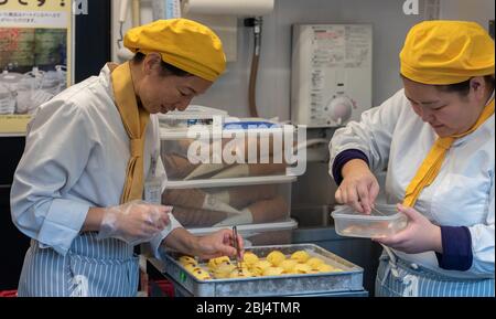 Two women chefs decorate street food in the shape of a cat, known as Maneki-neko, which is believed to bring good luck to the owner. Arashiyama, Kyoto Stock Photo