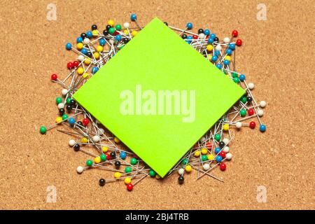 Stack of sticky notes surrounded with a bunch of colorful push pins Stock Photo