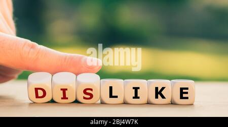 Hand turns dice and changes the expression "dislike" to "like". Stock Photo
