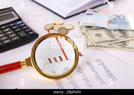 A magnifying glass on financial documents background, close-up Stock Photo