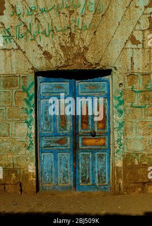 Weathered old blue painted wooden double doors in a village along the banks of the river Nile near Aswan Stock Photo