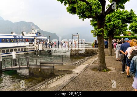 BELLAGIO, LAKE COMO - JUNE 2019: Queue of people waiting to board a passenger ferry at Bellagio on Lake Como. Stock Photo