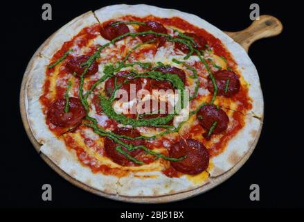 Thin crust beef pepperoni pizza with basil pesto sauce Stock Photo