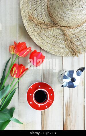 Tulips,straw hat ,saucer with coffee and  moka espresso maker on wooden background Stock Photo