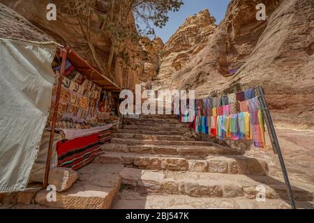 Passageways cut through the mountainous canyons of Petra in Jordan are lined with stands selling beautiful Bedouin crafts. Stock Photo