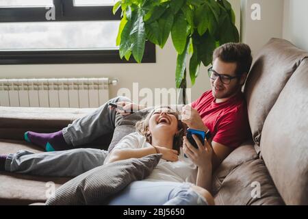 A couple on the sofa in the living room relaxed using the mobile phone. Stock Photo