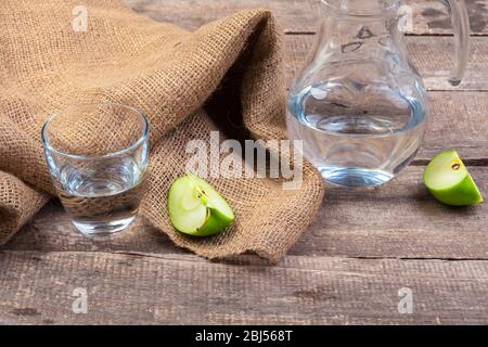 Dietary detox drink with apple slices in clean water and a fresh apple on a wooden table, close up Stock Photo