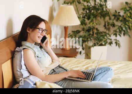 Beautiful young woman working on bed at home. Stock Photo