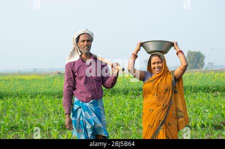 Happy indian rural farmer couple in agricultural field looking at each ...