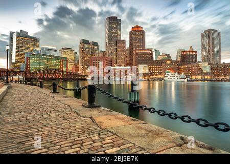 Downtown skyline city view of Boston Massachusetts USA looking over the riverfront harbor and marina boat dock from Fan Pier Park at night Stock Photo