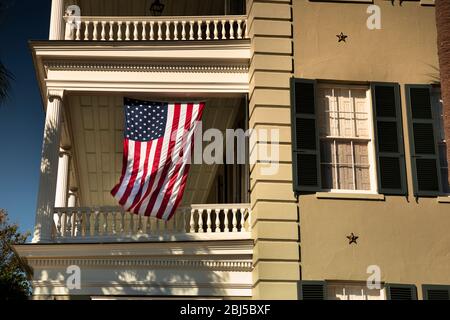 USA flag hangs from a front porch in the summer at a patriotic home in the USA Stock Photo