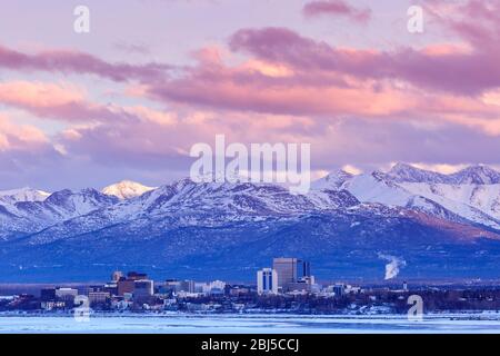 Anchorage Alaska skyline with Chugach mountains in background at sunset viewed across Cook inlet from Earthquake park in winter. Stock Photo