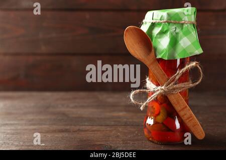 Canned red peppers in glass jar on wooden background Stock Photo