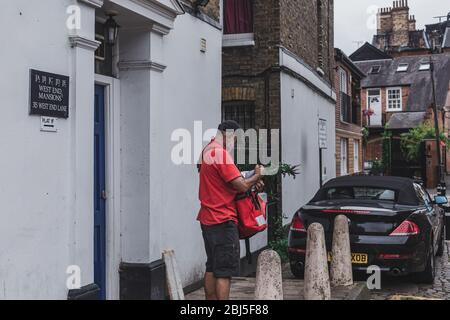 London/UK-30/7/18: Royal Mail's postman delivering mail. A mail satchel is a type of mailbag that a letter carrier uses over-the-shoulder for assistin Stock Photo