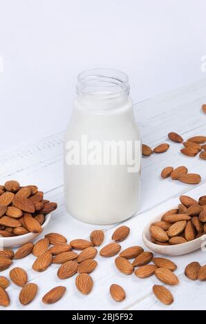 Almond milk in the bottle with almond nuts on white wooden background Stock Photo