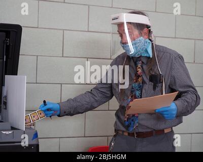 Baltimore, Maryland, USA. 28th Apr, 2020. A poll worker wearing protective gear reaches for I voted stickers at a voting center in Baltimore, MD. On April 28, 2020 a special election was held to fill the remainder of the term in the US House of Representatives for Maryland's 7th congressional district in the 116th U.S. Congress. Elijah Cummings, the incumbent representative, died in office on October 17, 2019. Credit: Sue Dorfman/ZUMA Wire/Alamy Live News Stock Photo