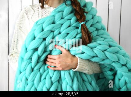 Woman wrapped in large knitted blanket Stock Photo