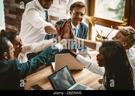 Happy Colleagues Joining Their Hands In High Five Gesture Stock Photo