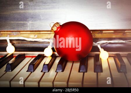 Piano keys decorated with decoration lights and red ball, close up Stock Photo