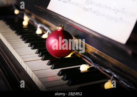 Piano keys decorated with decoration lights and red ball, close up Stock Photo