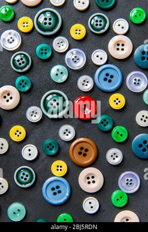 Colorful mixed sewing buttons on black background, flat lay. Top view. Stock Photo