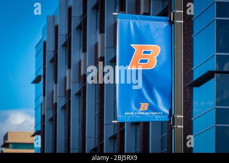 Boise State University 'B' logo banner flag in front of campus buildings and blue skies. Stock Photo