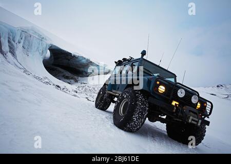 customised SUV standing in front of glacial ice cave on glacier Stock Photo