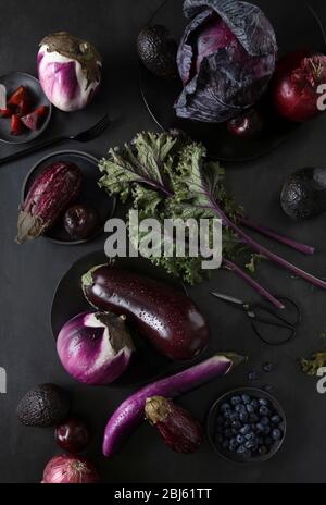 Still life with purple fruits and vegetables on wooden table with ...