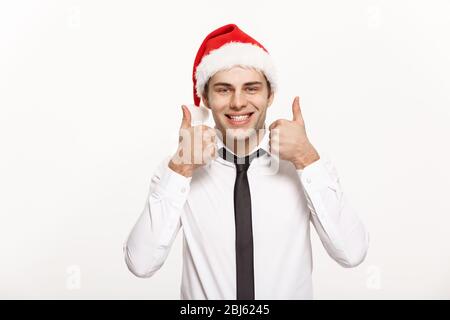 Christmas Concept - Handsome Business man wear santa hat showing thump up on white isolated background. Stock Photo