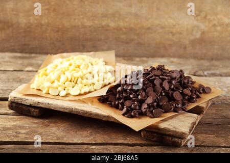 Chocolate morsels on board, on wooden background Stock Photo