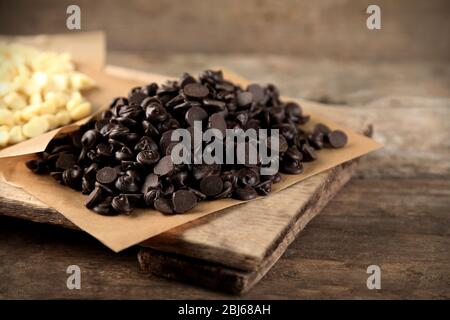 Chocolate morsels on board, on wooden background Stock Photo