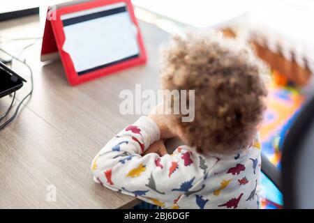 Child doing using digital tablet during online conference with teachers and classmates Stock Photo