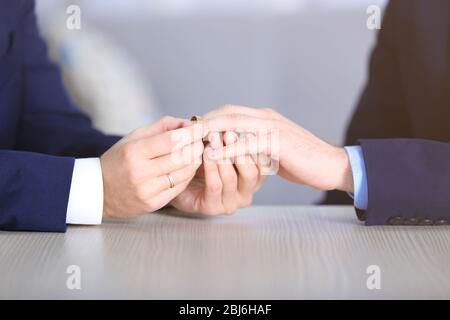 One groom placing the ring on another man's finger Stock Photo