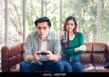 Portrait of Woman Feeling Offended With Her Boyfriend When He Playing Video Games While Sitting on The Couch in Living Room. Couple Love Relationship Stock Photo