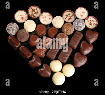 Assorted chocolate candies in form of heart on black background Stock Photo