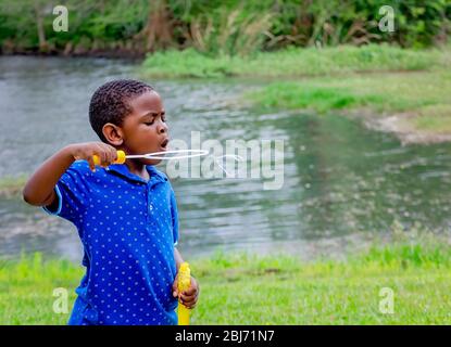 A boy blows bubbles at Langan Park, April 13, 2019, in Mobile, Alabama. The 720-acre park offers a wide variety of recreation opportunities. Stock Photo