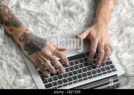 Young man with tattoo using laptop on a floor at home Stock Photo